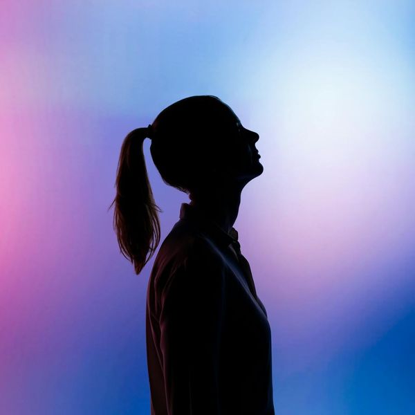Profile of a woman in a focused yoga pose against a minimal background.